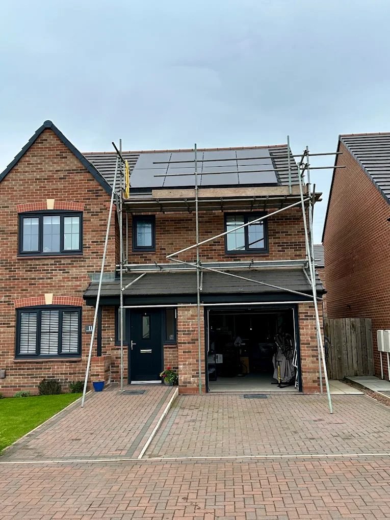 Black solar panels newly fitted on the front roof of a brick house