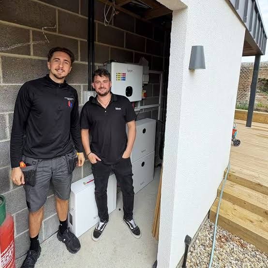Two of the G Phillips team beside a finished solar inverter and battery storage install